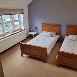 a bedroom with two beds and a table and two windows at Cosy modern cottage by the sea, heart of snowdonia in Llwyngwril