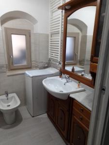 een badkamer met een wastafel, een toilet en een spiegel bij Dimora del Malconsiglio in Miglionico