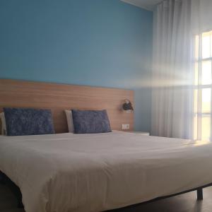 1 dormitorio con 1 cama blanca grande con almohadas azules en Flag Hotel Santarém, en Pernes