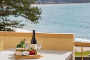 テリガルにあるOceans at Terrigal a Beachfront Oasisのワイン1本とグラスをテーブルに用意しています。