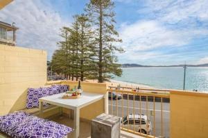 a balcony with a table and chairs and a view of the water at Oceans at Terrigal a Beachfront Oasis in Terrigal