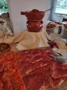 a table topped with meat and a bowl of food at Hotel La Fattoria Sul Mare in Capo Vaticano