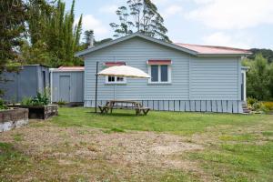 una casa con tavolo da picnic e ombrellone di The Farmhouse Kaeo Whangaroa a Kaeo