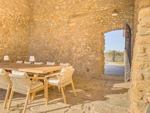 una mesa de madera y sillas en una habitación con una pared de piedra en Mas Maria Carmen Dalmau en Sant Andreu del Terri