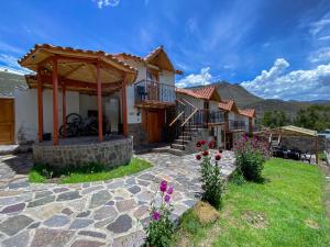 een huis met een stenen patio en een prieel bij Lodge El Portal de Qopuy in Coporaque
