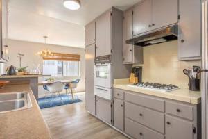 uma cozinha com armários brancos e um forno com placa de fogão em Downtown Manhattan Beach 3 Bed Townhouse Parking em Manhattan Beach