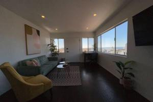 マンハッタン・ビーチにあるOcean View 1 Bedroom Manhattan Beachのリビングルーム(緑のソファ、大きな窓付)