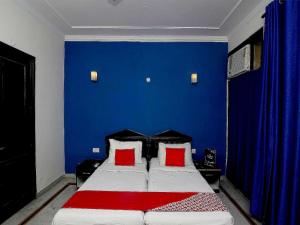 a bedroom with a blue wall and a bed with red pillows at Golden Cafe in Chennai
