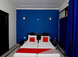 a bedroom with a blue wall and a bed with red pillows at Golden Cafe in Chennai