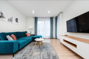 a living room with a blue couch and a flat screen tv at Posejdon - BillBerry Apartments in Gdańsk
