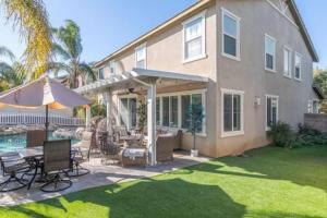 a house with an umbrella and a table and chairs at Minutes to Wineries Outdoor Oasis Pool Table in Murrieta