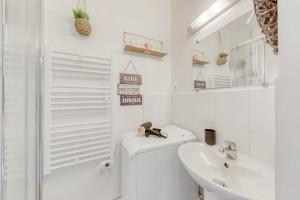 La salle de bains blanche est pourvue d'un lavabo et de toilettes. dans l'établissement Le Peper - RER B - La place - Paris - Orly, à Arcueil