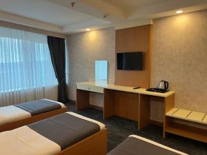 a hotel room with two beds and a desk with a television at E5 PARK OTEL in Esenyurt