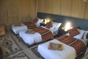 um quarto de hotel com quatro camas com toalhas em Merzouga Luxury Tent em Merzouga