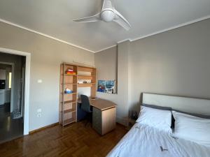 a bedroom with a bed and a desk with a ceiling fan at Promenade city apartment in Thessaloniki
