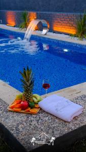 a tray of fruit and a glass of wine next to a swimming pool at Şile SHAMAN BUNGALOW VİLLAS 102 in Şile