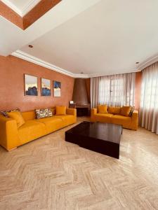 uma sala de estar com dois sofás amarelos e uma mesa de centro em Villa Dune Rouge de la Siesta em Mohammedia