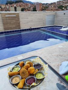 un plato de comida en una mesa junto a una piscina en HOTEL CALIFORNIA CITY, en Medellín