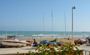 una spiaggia con barche e persone sulla spiaggia di Fly Home Sicily a Marina di Ragusa