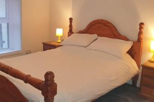 una camera da letto con un letto con lenzuola bianche e due lampade di Eden Rose Cottage a Morecambe