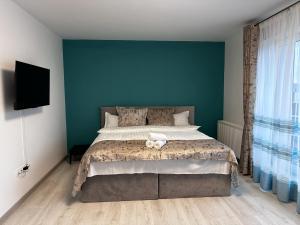 a bedroom with a large bed with a blue wall at elisio - Glide Studio in Braşov