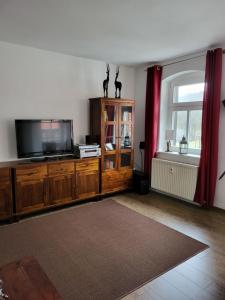 a living room with a tv on a wooden entertainment center at Ferienwohnung Detlef Pascher in Oybin