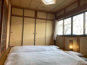 - une chambre avec un grand lit blanc et des fenêtres dans l'établissement 雲海と星空の宿 YAKUNO, à Fukuchiyama