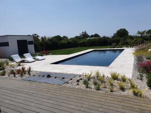 una piscina en un jardín con 2 tumbonas en Maison contemporaine, en Mondoubleau