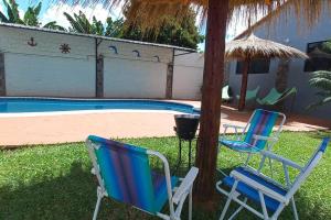 duas cadeiras e um guarda-sol junto a uma piscina em Mar Azul em San Lorenzo