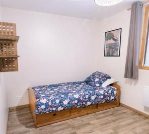 ein kleines Schlafzimmer mit einem Bett mit Blumenkissen in der Unterkunft Gite aux 1000 chemins - Apt 50m2 in Saint-Joseph-de-Rivière