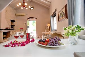 una mesa con una bandeja de fruta y copas de vino en Studio Petrino - A holiday nest!, en Velianitátika