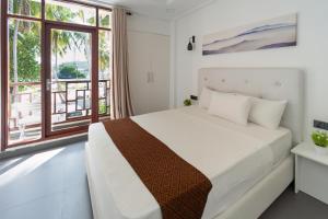 een slaapkamer met een bed en een groot raam bij Silver Oasis Maldives in Huraa
