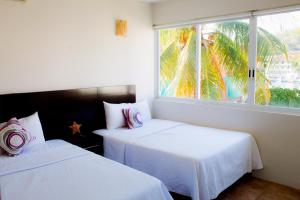 two beds in a room with a window at La Playa departamento suites in Santa Cruz Huatulco