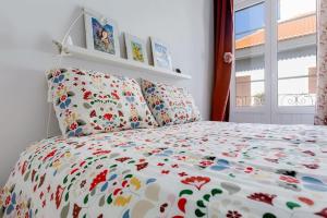 a bedroom with a bed with a floral bedspread at Requinte e bom gosto para 6 pessoas no coração de Faro in Faro