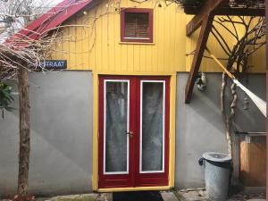 una casa con una puerta roja a un lado. en Tiny house for 2 with private garden en Utrecht