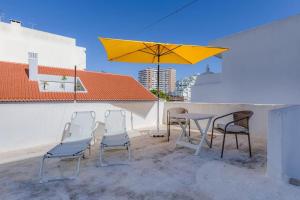 a patio with a table and chairs and a yellow umbrella at Requinte e bom gosto para 6 pessoas no coração de Faro in Faro