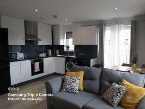 a living room with a couch and a kitchen at Cosy 2 bed apartment with parking & b/fast cereal 