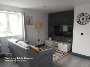 a living room with a couch and a tv at Cosy 2 bed apartment with parking & b/fast cereal 