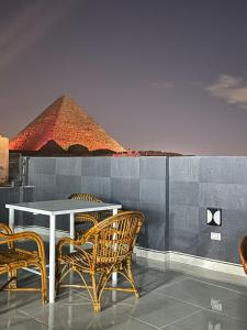 Prince Pyramids Inn في القاهرة: طاولة وكراسي مع وجود هرم في الخلفية