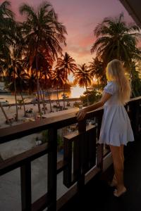 a woman standing on a balcony looking at the beach at Silver Oasis Maldives in Huraa