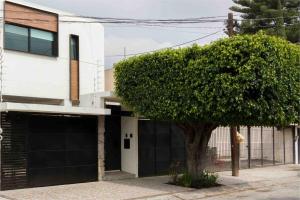un árbol frente a un edificio con garaje en Belmalí Zen, lujo y confort/Jacuzzi privado a.c. ., en Guadalajara