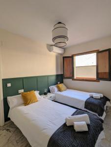 two beds in a hotel room with a window at Ático San Juan 2 in Cáceres