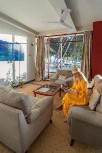 a woman sitting on a couch reading a book at Silver Oasis Maldives in Huraa