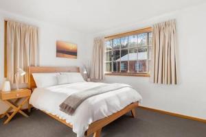 a bedroom with a large bed and a window at Cosy renovated 2 bed villa in superb location in Hobart