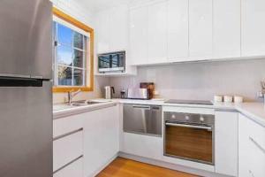 a kitchen with white cabinets and stainless steel appliances at Cosy renovated 2 bed villa in superb location in Hobart