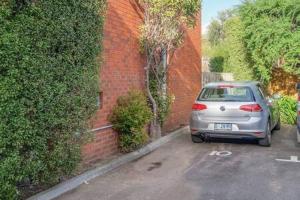 a car parked in a parking lot next to a brick wall at Cosy renovated 2 bed villa in superb location in Hobart