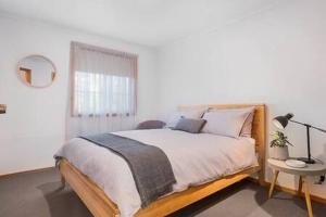 a white bedroom with a large bed and a lamp at Cosy renovated 2 bed villa in superb location in Hobart