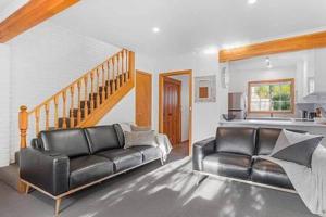 a living room with a leather couch and a staircase at Cosy renovated 2 bed villa in superb location in Hobart +15 photos