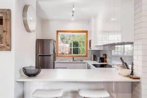 a white kitchen with a counter and a refrigerator at Cosy renovated 2 bed villa in superb location in Hobart