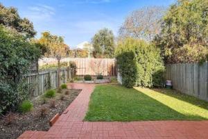 a backyard with a fence and a brick walkway at Cosy renovated 2 bed villa in superb location in Hobart